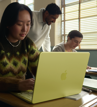 Estudiante utilizando un MacBook Neo, color cítrico, portátil sin enchufar en un aula