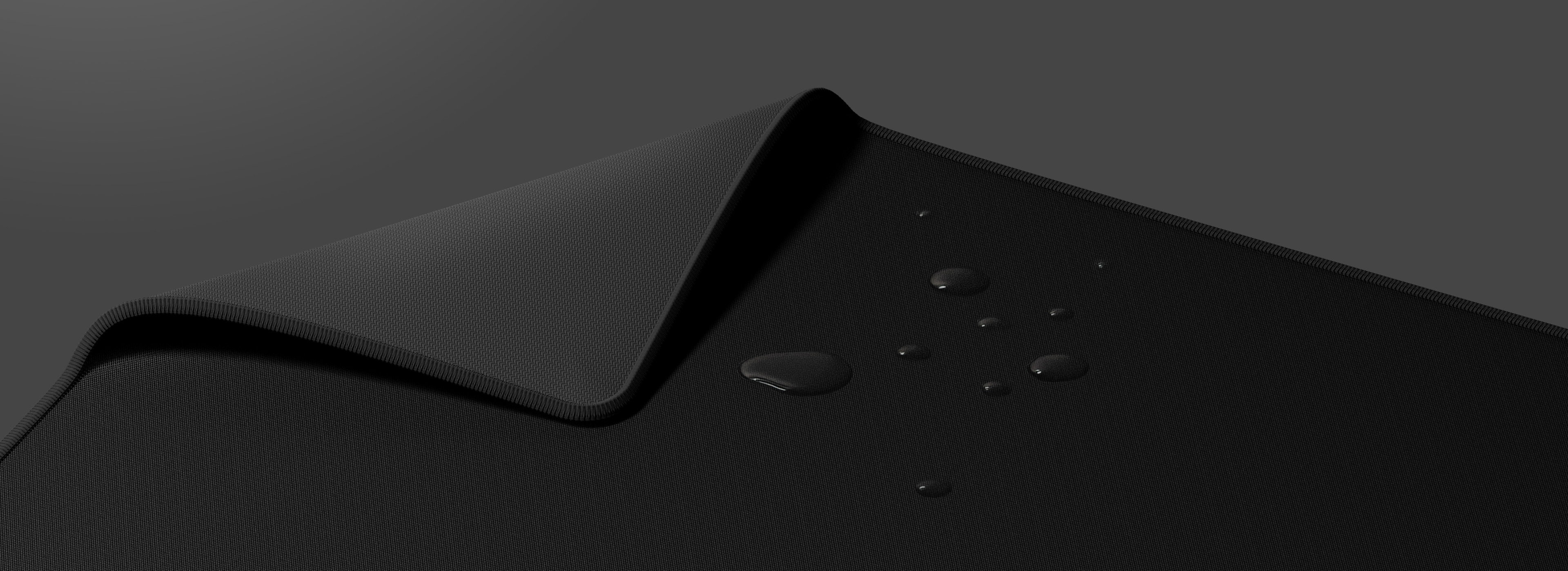 Large black mouse pad with a textured surface and water droplets on it