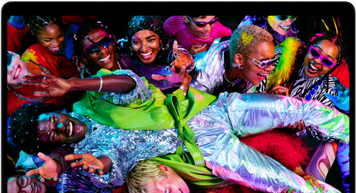 MacBook Pro con la pantalla a todo color que muestra a una persona llevada en volandas en una fiesta, destaca la nitidez de la pantalla Liquid Retina XDR