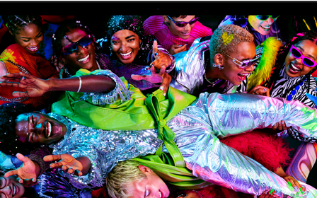 MacBook Pro con la pantalla a todo color que muestra a una persona llevada en volandas en una fiesta, destaca la nitidez de la pantalla Liquid Retina XDR