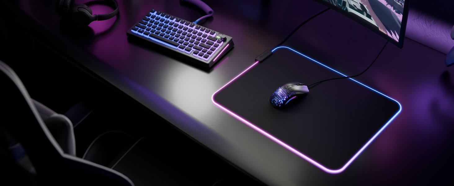 Spelopstelling in een donkere omgeving met RGB-verlicht toetsenbord en muis op het bureau. Paarse sfeerverlichting zorgt voor een dramatisch spelsfeereffect.