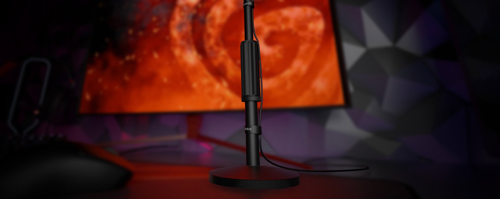 Microphone on a stand with a cable, set against a colorful background and computer monitor