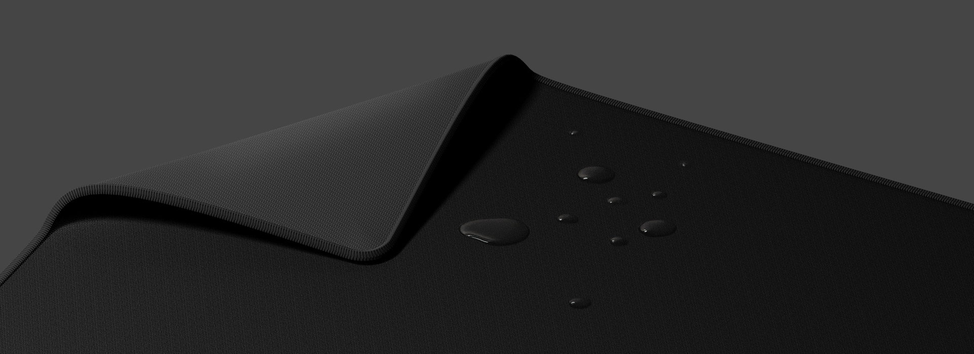 Large black mouse pad with a textured surface and water droplets on it